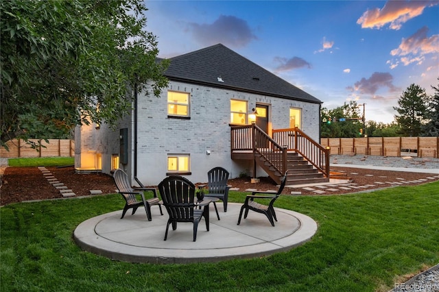 back house at dusk with an outdoor fire pit, a lawn, and a patio area