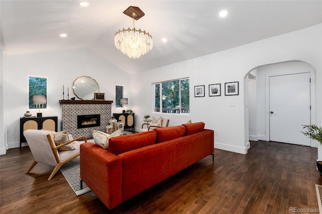 living room featuring lofted ceiling, dark hardwood / wood-style floors, an inviting chandelier, and a fireplace