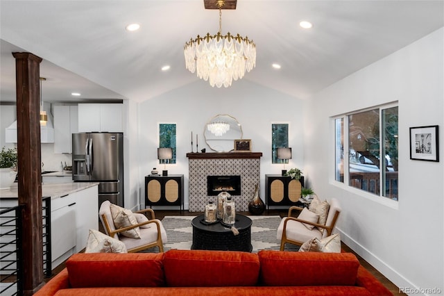 living room with ornate columns, vaulted ceiling, a fireplace, wood-type flooring, and a chandelier