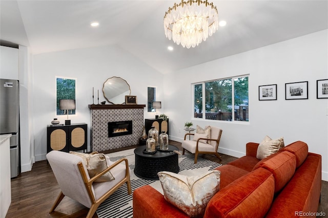 living room with a tile fireplace, lofted ceiling, a notable chandelier, and dark hardwood / wood-style flooring