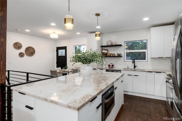 kitchen featuring pendant lighting, sink, appliances with stainless steel finishes, white cabinetry, and a kitchen island