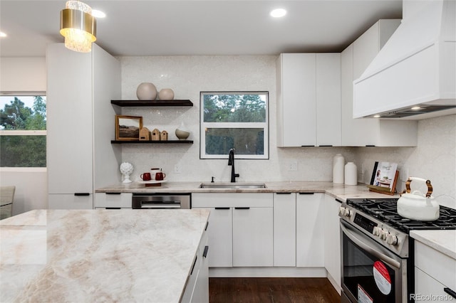 kitchen with stainless steel gas stove, sink, white cabinetry, and premium range hood