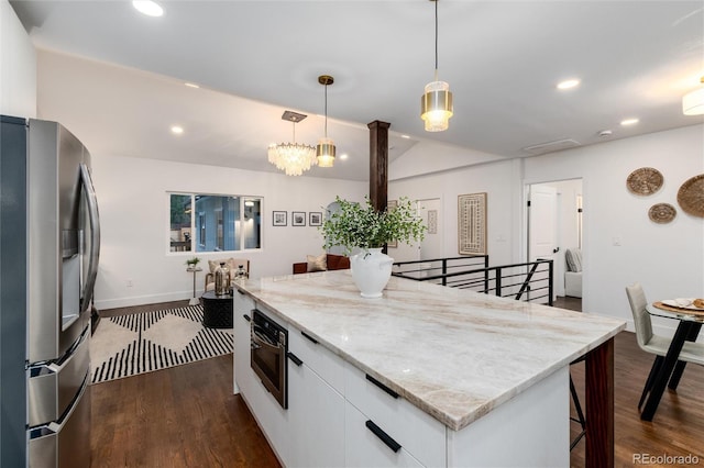 kitchen with white cabinetry, hanging light fixtures, dark hardwood / wood-style flooring, stainless steel fridge, and light stone countertops