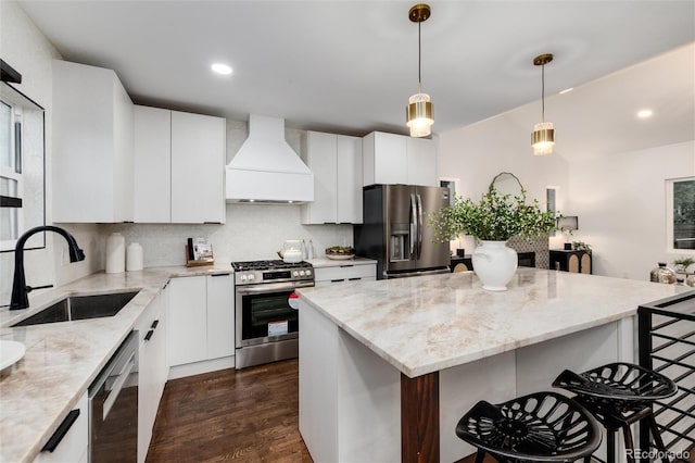 kitchen with premium range hood, sink, white cabinetry, light stone counters, and stainless steel appliances