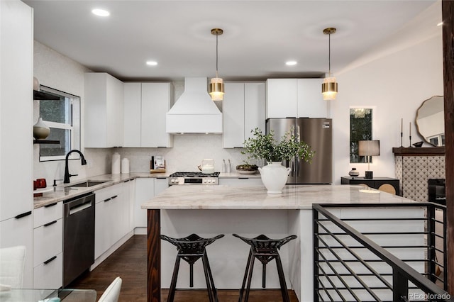 kitchen featuring sink, custom exhaust hood, appliances with stainless steel finishes, light stone countertops, and white cabinets