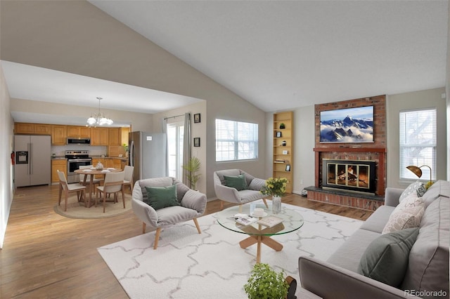 living room with vaulted ceiling, light wood-type flooring, an inviting chandelier, and a fireplace