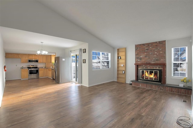 unfurnished living room featuring an inviting chandelier, a brick fireplace, dark wood-type flooring, and vaulted ceiling