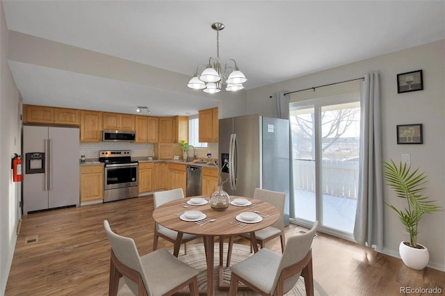 dining space featuring sink, a chandelier, and light wood-type flooring