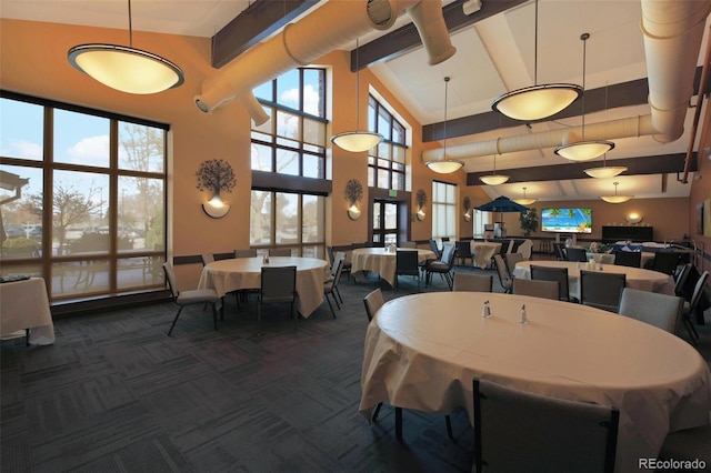 dining space with beamed ceiling, dark carpet, and a high ceiling