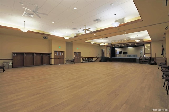 workout room with ceiling fan, wood-type flooring, and a tray ceiling