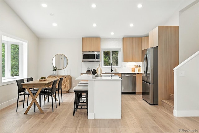 11635 W Security Ave, Lakewood, CO 80401 - kitchen featuring stainless steel appliances, a kitchen island, a breakfast bar area, light countertops, and modern cabinets