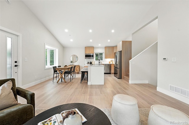 11635 W Security Ave, Lakewood, CO 80401 - living room featuring plenty of natural light, light wood-style floors, vaulted ceiling, recessed lighting, and stairs
