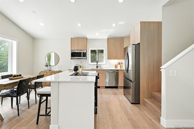 11635 W Security Ave, Lakewood, CO 80401 - kitchen with appliances with stainless steel finishes, a kitchen island, a breakfast bar, modern cabinets, and light countertops