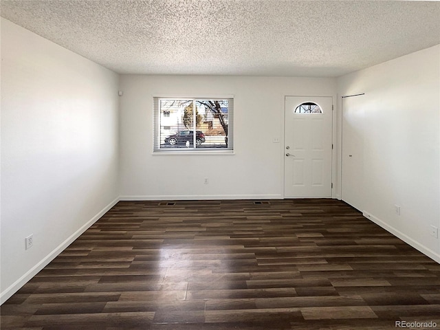 foyer featuring a textured ceiling, wood finished floors, and baseboards