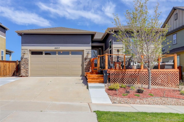 view of front of property with fence, an attached garage, concrete driveway, and stone siding