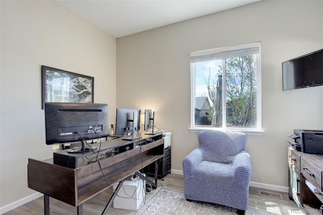 office with baseboards, visible vents, and wood finished floors