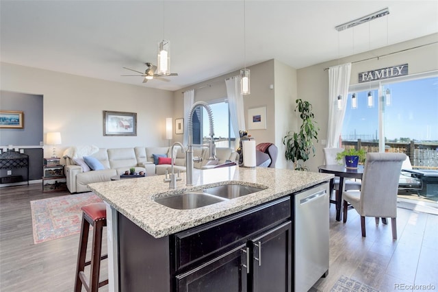 kitchen featuring a sink, open floor plan, wood finished floors, and dishwasher