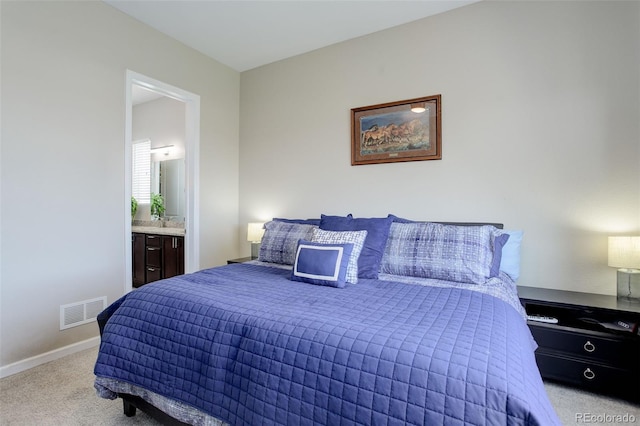 bedroom with baseboards, visible vents, light carpet, and ensuite bath