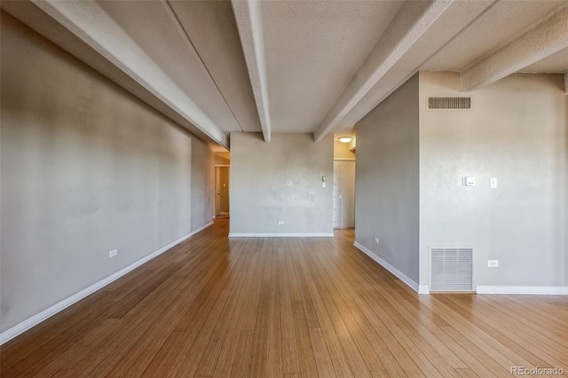 spare room featuring visible vents, baseboards, and hardwood / wood-style flooring