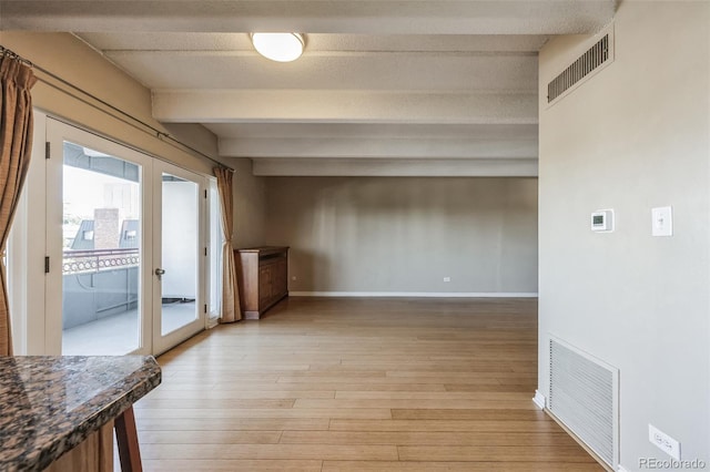 unfurnished living room with beamed ceiling, light wood-style flooring, french doors, and visible vents