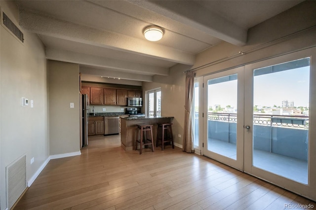 kitchen featuring stainless steel appliances, a kitchen bar, dark countertops, and visible vents