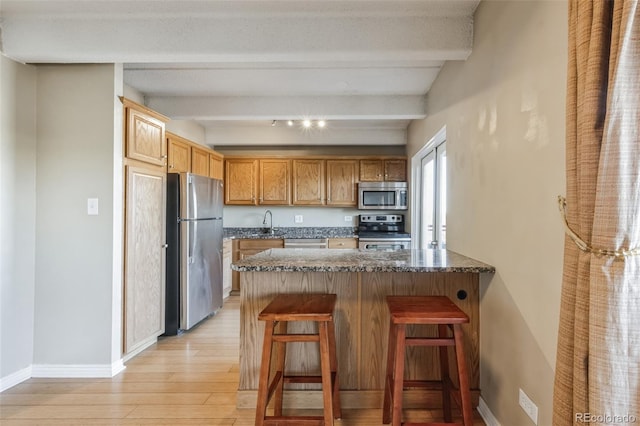 kitchen featuring appliances with stainless steel finishes, baseboards, light wood-style floors, and a peninsula