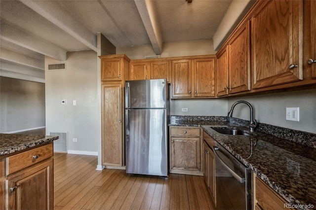 kitchen featuring visible vents, a sink, beam ceiling, stainless steel appliances, and wood-type flooring