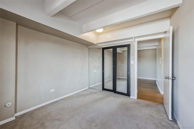 unfurnished bedroom featuring beamed ceiling, carpet flooring, and baseboards