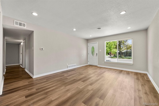 971 Ursula St, Aurora, CO 80011 - unfurnished living room featuring a textured ceiling, wood finished floors, baseboards, and recessed lighting