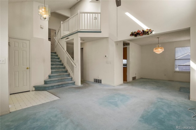 interior space with visible vents, light colored carpet, a high ceiling, stairs, and a notable chandelier