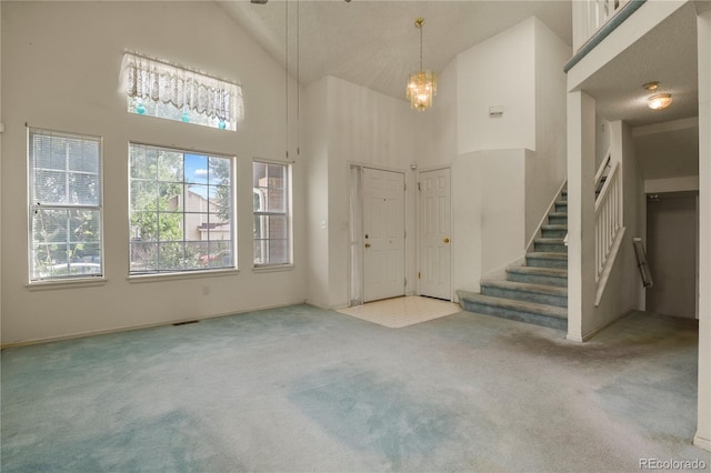 carpeted foyer entrance featuring stairs and high vaulted ceiling