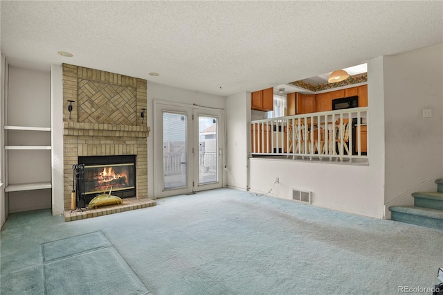 unfurnished living room with carpet floors, a fireplace, visible vents, stairway, and a textured ceiling