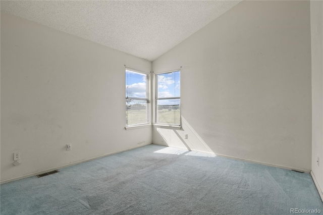 unfurnished room featuring vaulted ceiling, a textured ceiling, visible vents, and light colored carpet