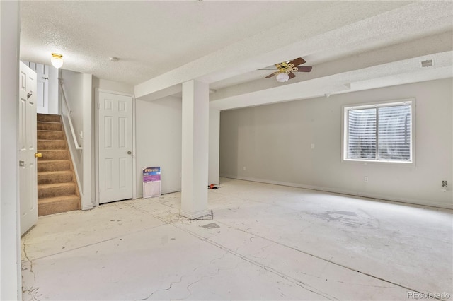 basement with a textured ceiling, ceiling fan, and stairway