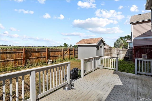 deck with a fenced backyard, an outdoor structure, and a storage shed