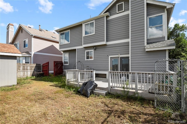 back of house featuring fence, a wooden deck, and a lawn