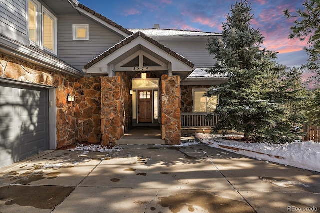 exterior entry at dusk featuring a garage