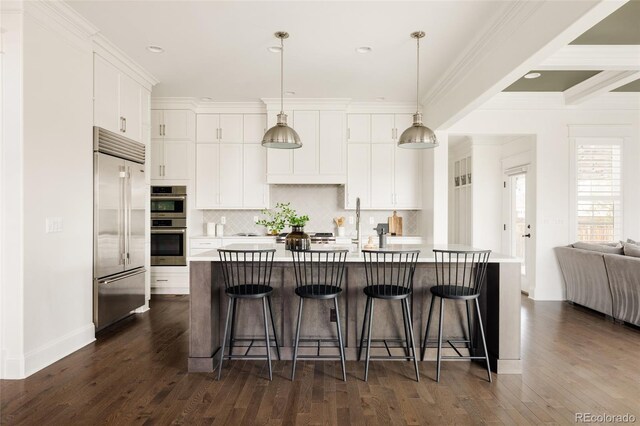 kitchen with white cabinets, dark wood-style flooring, light countertops, stainless steel appliances, and backsplash