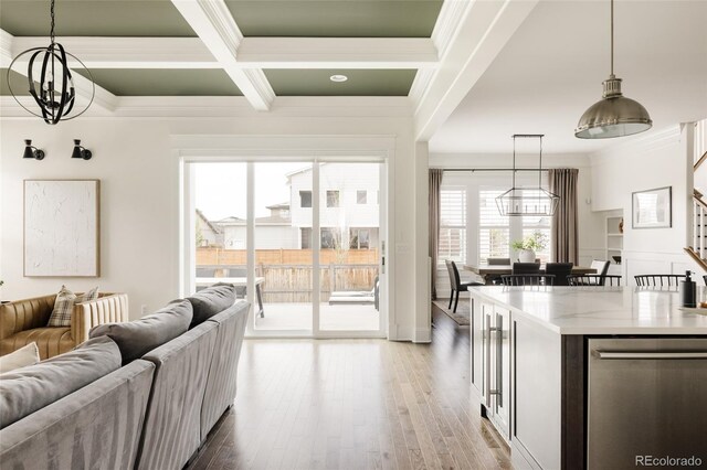 living area featuring ornamental molding, beam ceiling, coffered ceiling, light wood finished floors, and a notable chandelier