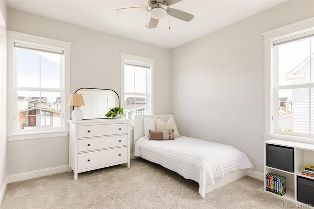 bedroom with light colored carpet, baseboards, and multiple windows