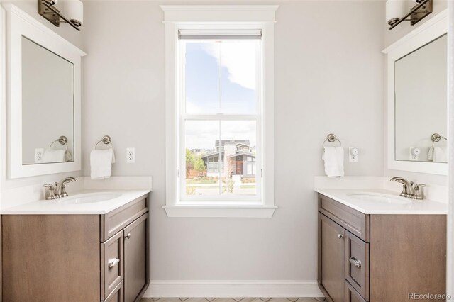 bathroom with baseboards, two vanities, and a sink