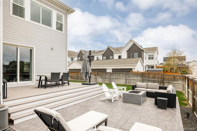 view of patio with a fenced backyard, an outdoor living space with a fire pit, a residential view, and cooling unit