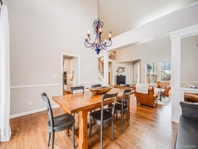 dining space featuring hardwood / wood-style floors, crown molding, decorative columns, and a chandelier