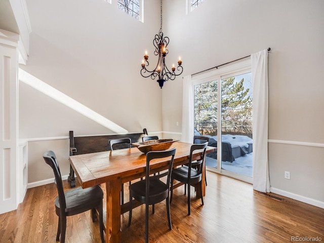 dining room featuring hardwood / wood-style flooring, a chandelier, and a high ceiling