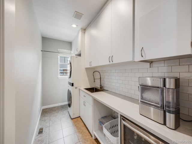 washroom with cabinets, sink, stacked washer / drying machine, and light tile patterned floors