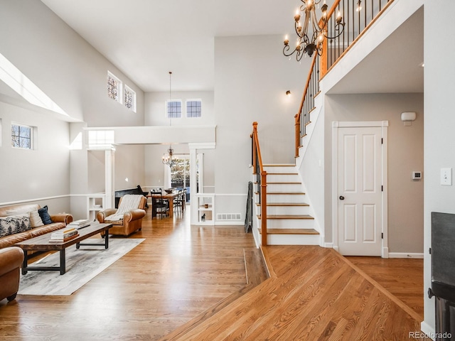 living room featuring an inviting chandelier, a high ceiling, and hardwood / wood-style flooring