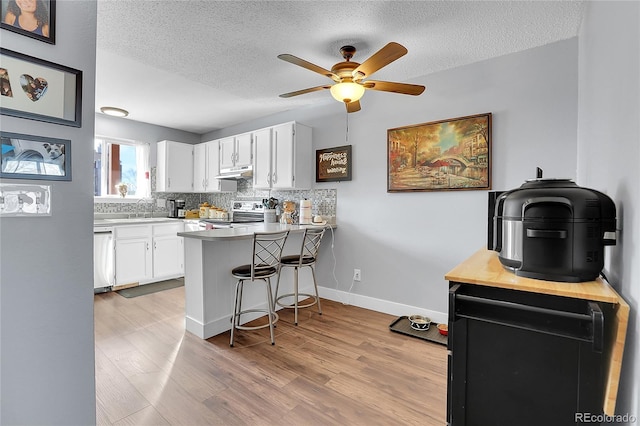 kitchen with kitchen peninsula, white cabinetry, light hardwood / wood-style flooring, stainless steel electric range oven, and a breakfast bar area