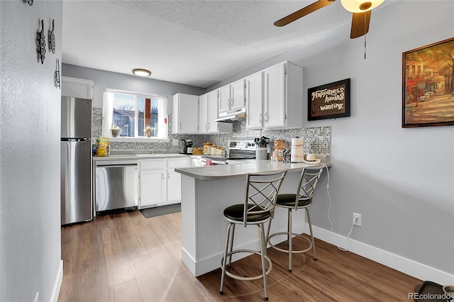 kitchen with kitchen peninsula, appliances with stainless steel finishes, white cabinets, and sink