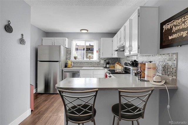 kitchen with kitchen peninsula, white cabinetry, sink, and stainless steel appliances