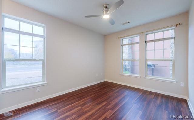 13456 Via Varra Unit 114, Broomfield, CO 80020 - spare room featuring visible vents, dark wood-style flooring, a healthy amount of sunlight, baseboards, and ceiling fan